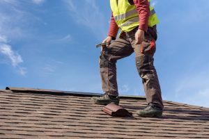 Worker standing on asphalt shingle roof