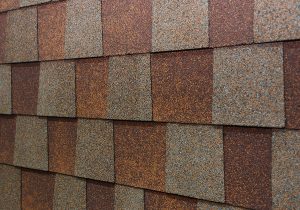 A close-up of a brown and gray asphalt roof shingles 