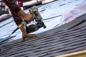 Worker installing grey roof shingles