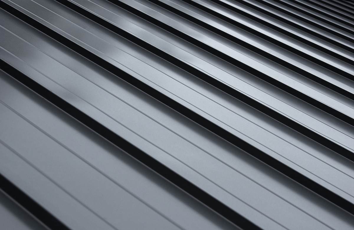 Close-up view of a metallic roofing with parallel ridges, showcasing a sleek, reflective gray finish