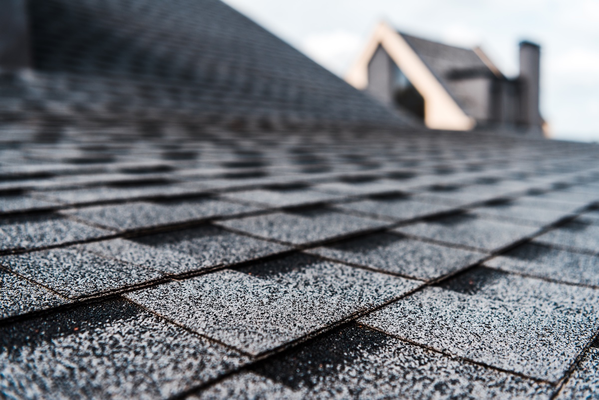 Close-up view of gray asphalt roof shingles, with the focus on the textured surface